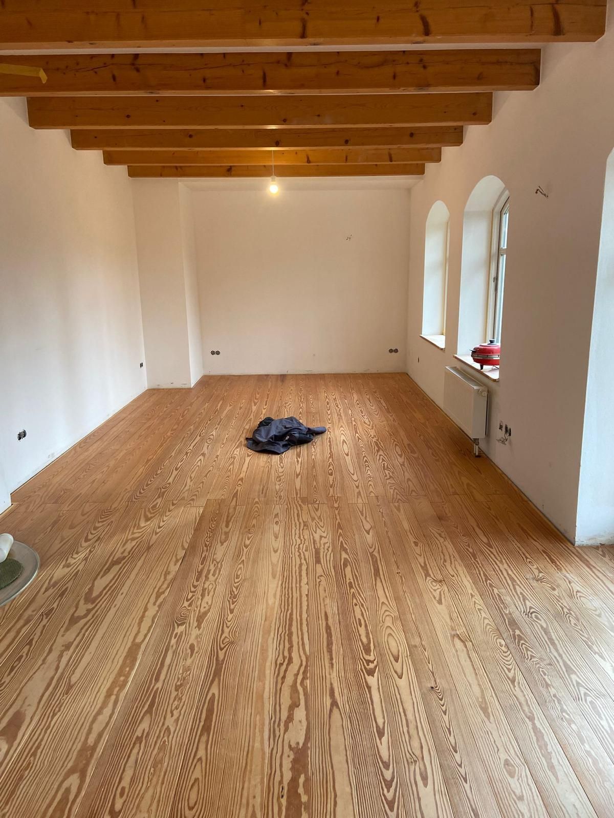 Ein großer leerer Raum mit Holzboden und weißen Wänden.