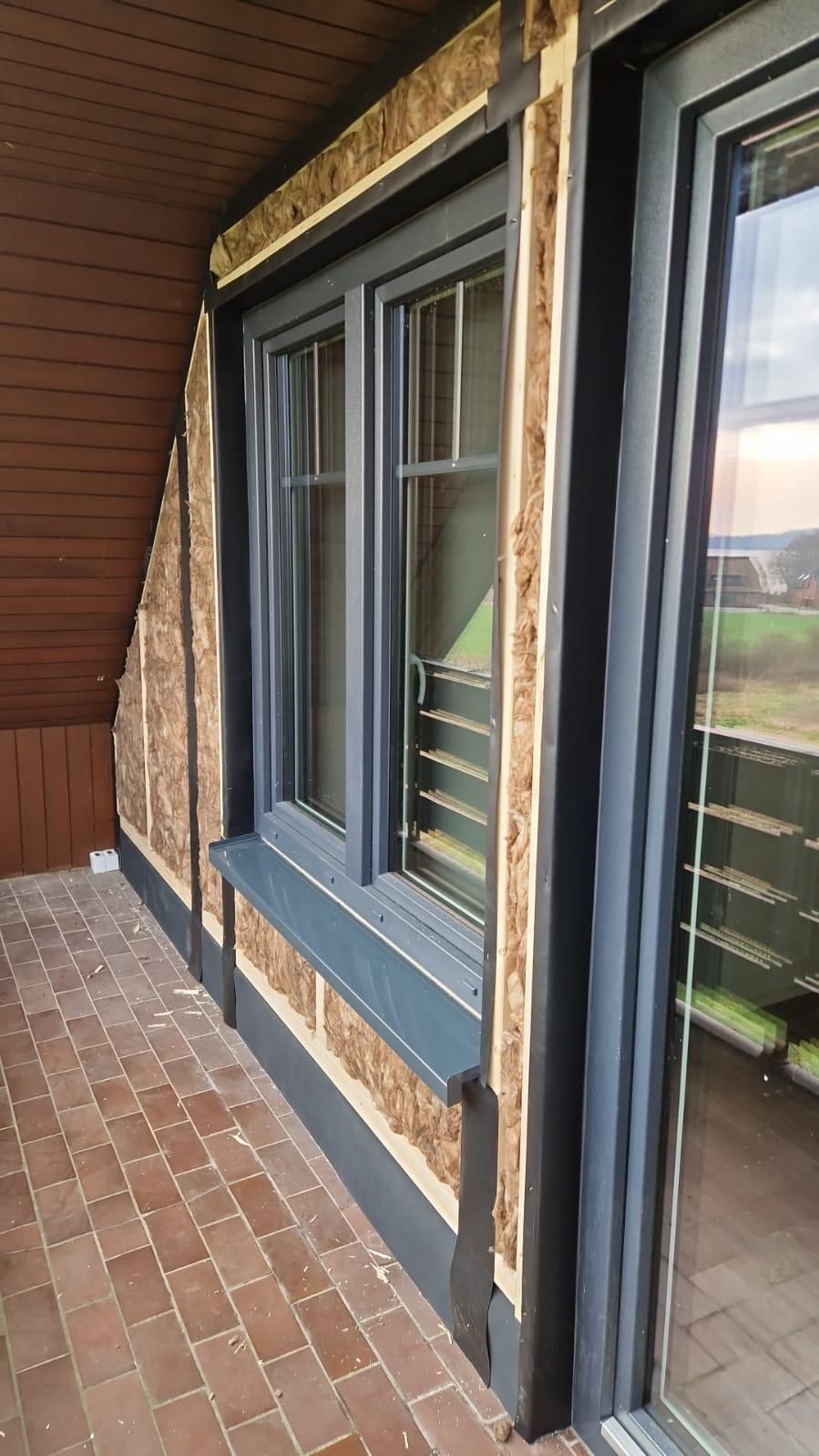 Ein Balkon mit zwei Fenstern und einer Glasschiebetür.