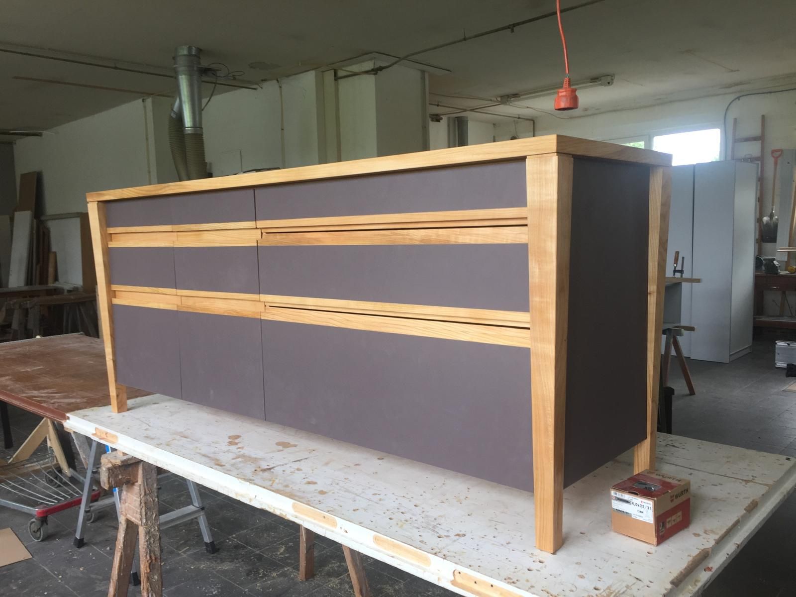 Auf einem Holztisch steht eine Holzkommode.