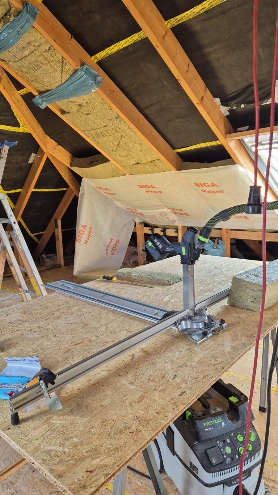 Ein Holztisch mit einem Staubsauger darauf auf einem Dachboden.