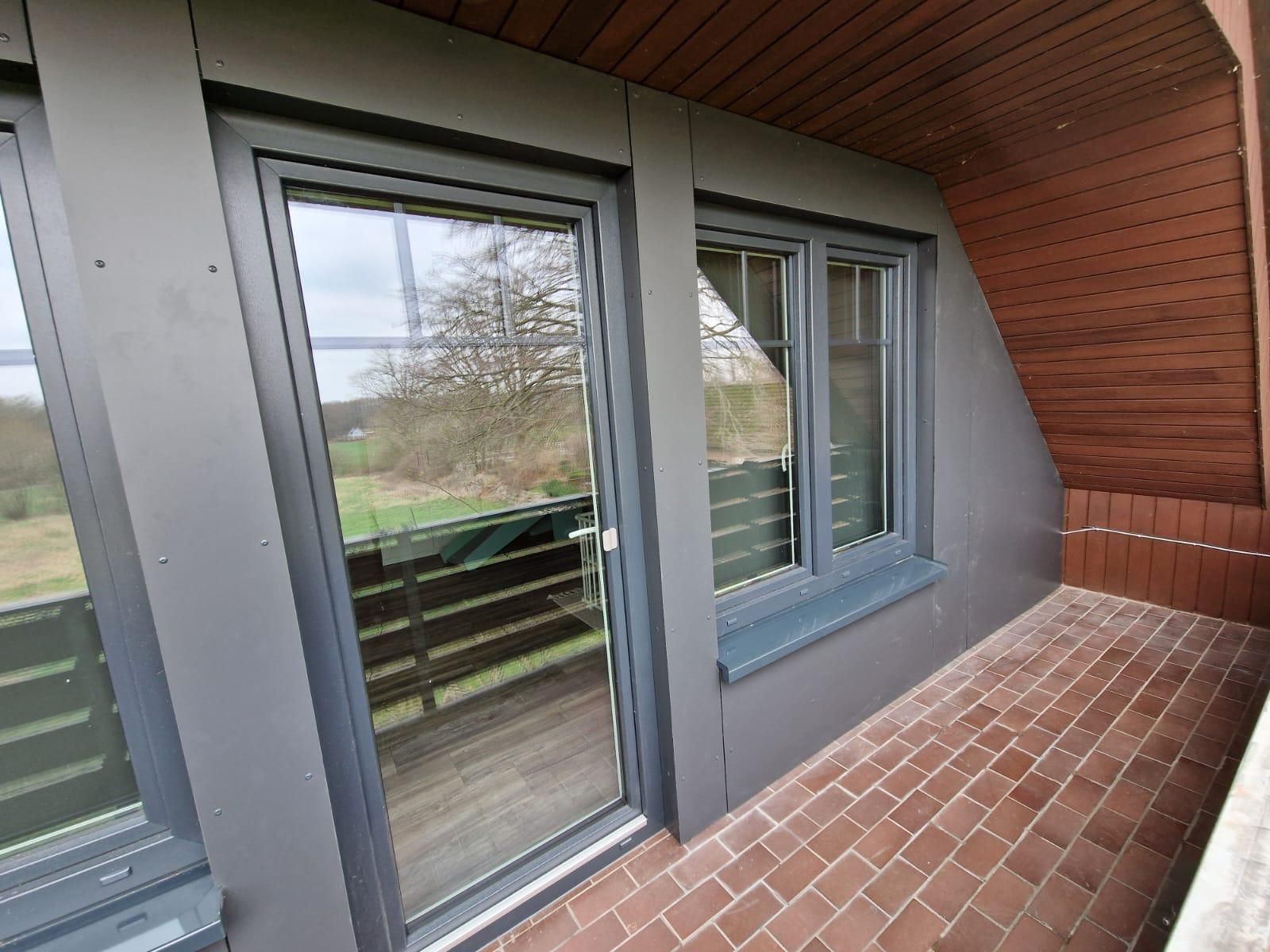 Ein Balkon mit Glasschiebetür und zwei Fenstern