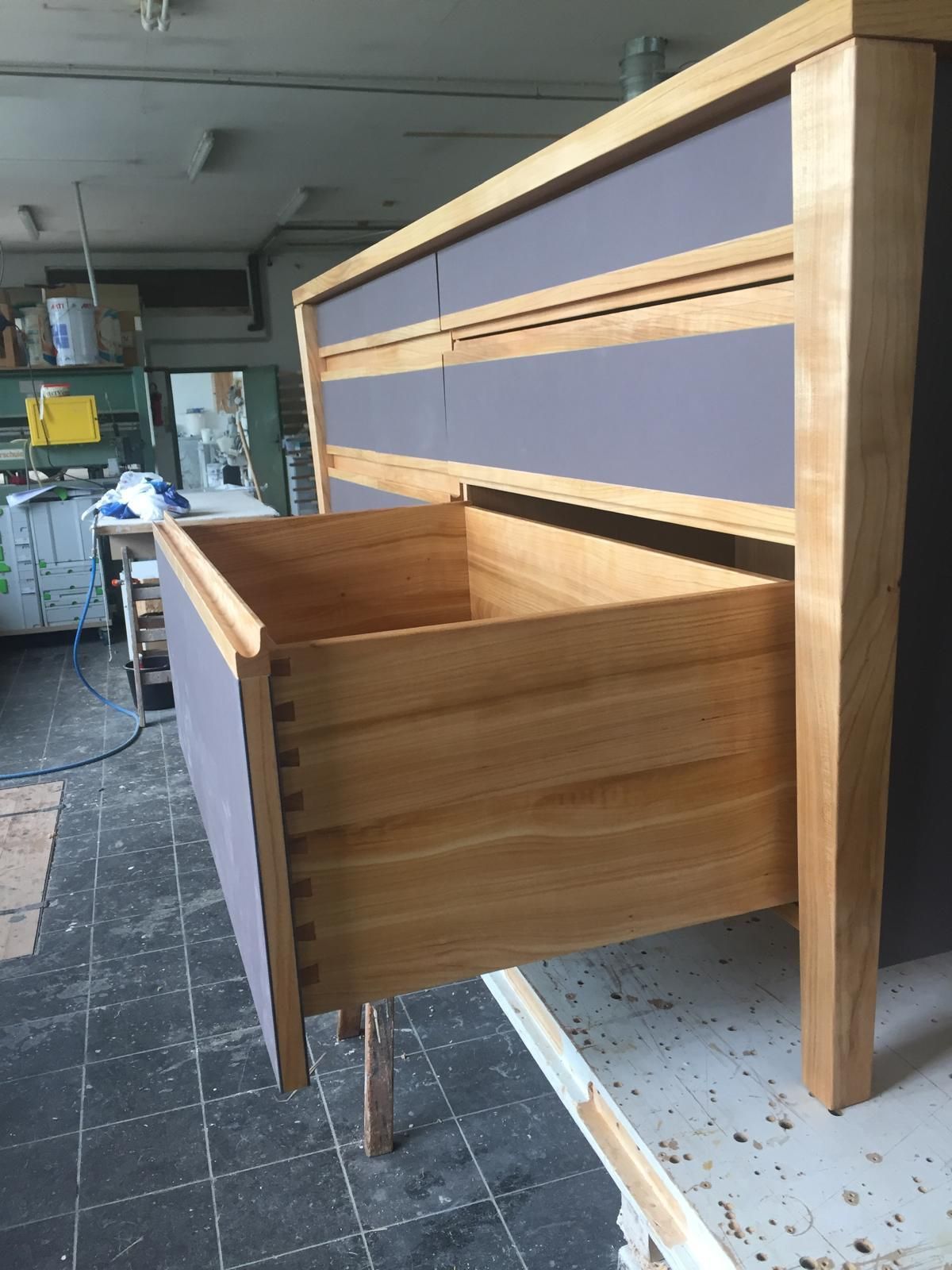 Eine Holzkommode mit einer offenen Schublade in einer Werkstatt