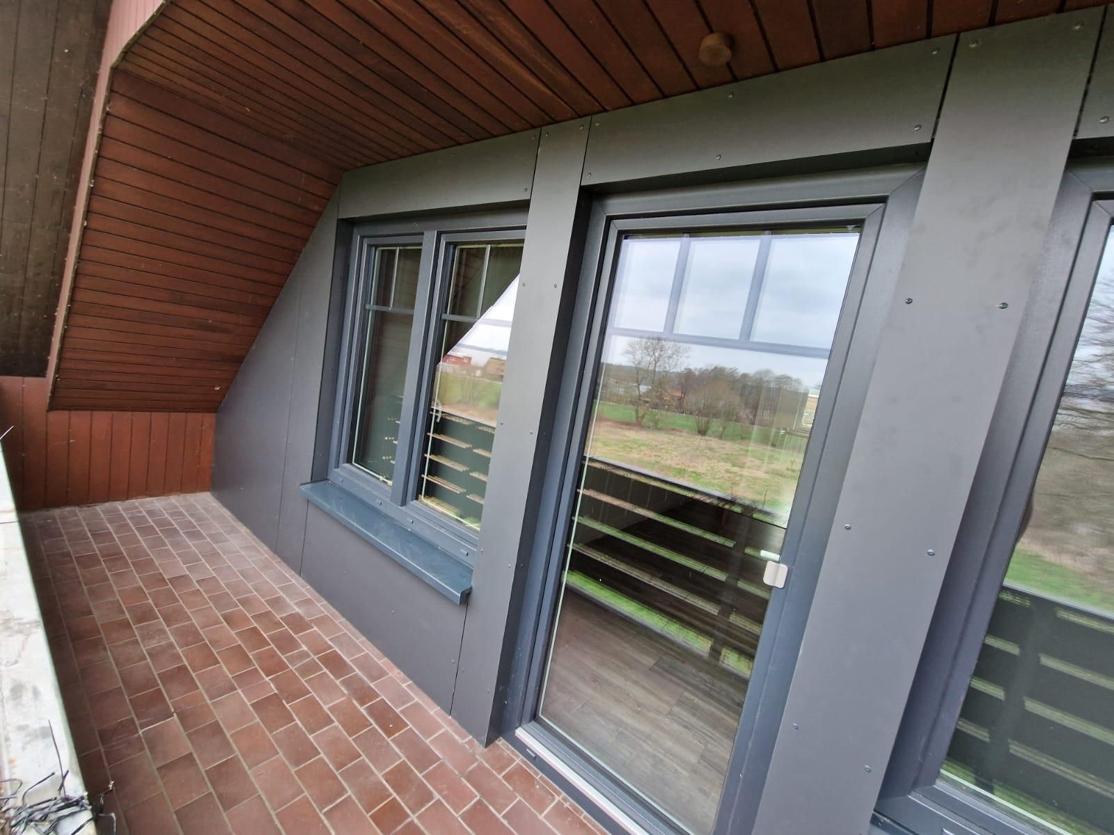 Ein Balkon mit Glasschiebetür und zwei Fenstern