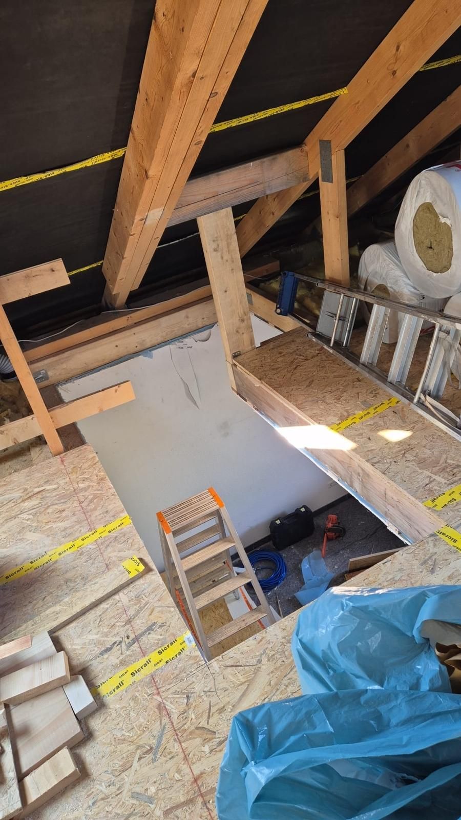Auf dem Dachboden eines im Bau befindlichen Gebäudes steht eine Leiter.