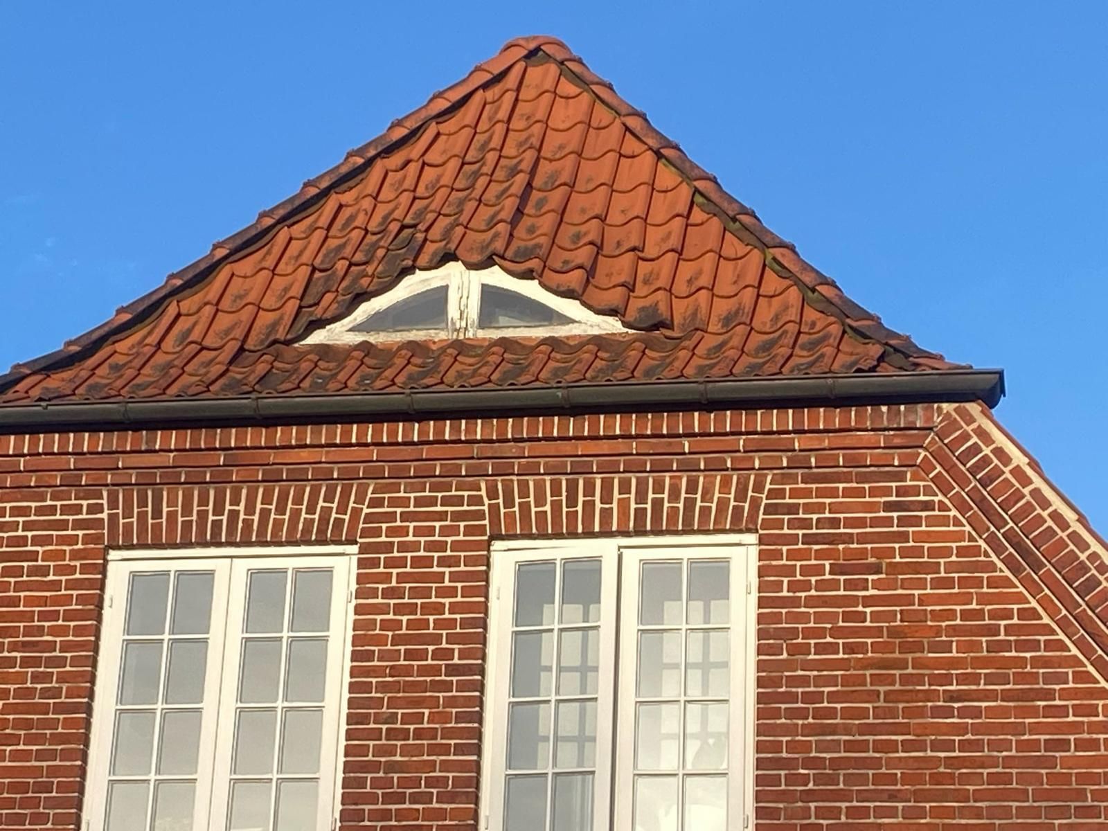 Ein Backsteingebäude mit rotem Dach und weißen Fenstern