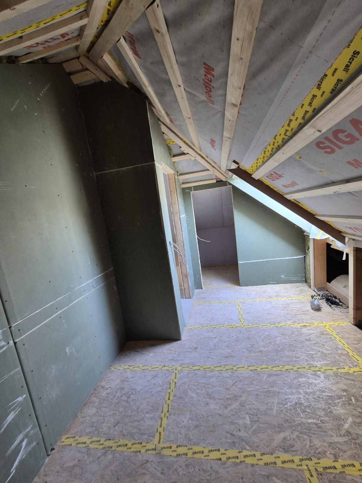 Ein Raum mit einer Holzdecke und einem gelben Klebeband auf dem Boden.