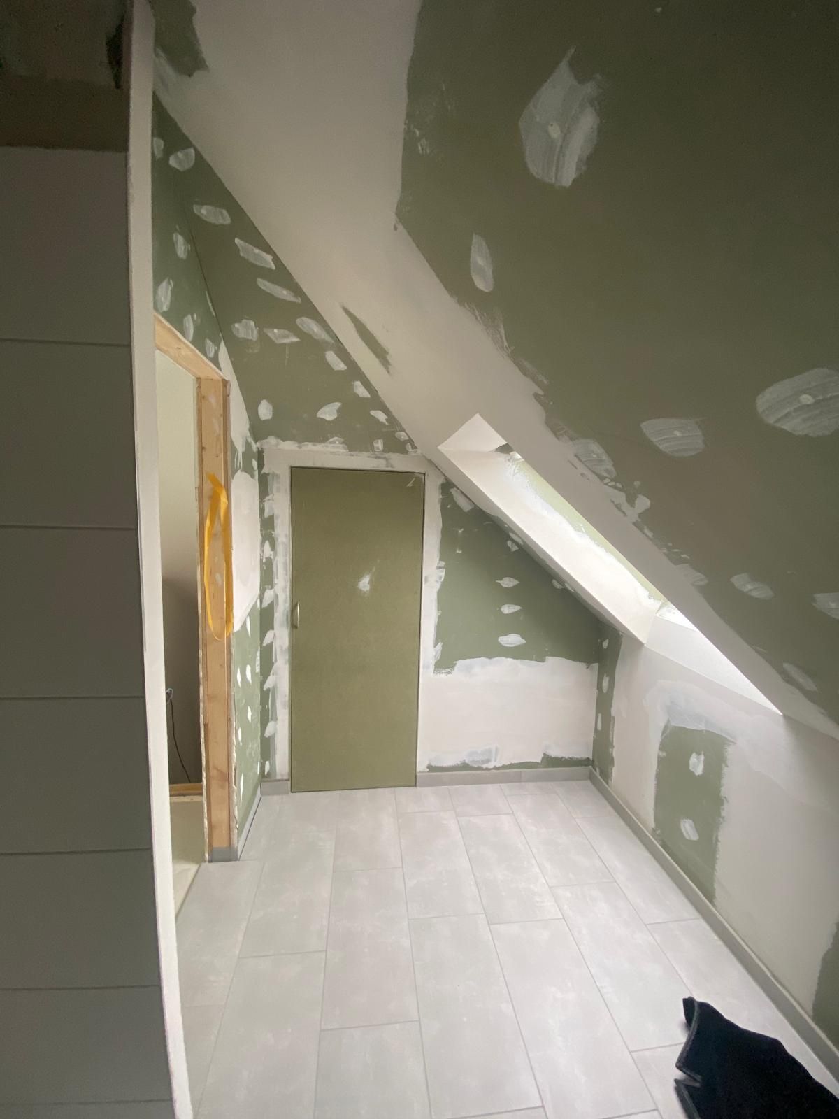 Ein Raum mit schräger Decke und einer Tür.