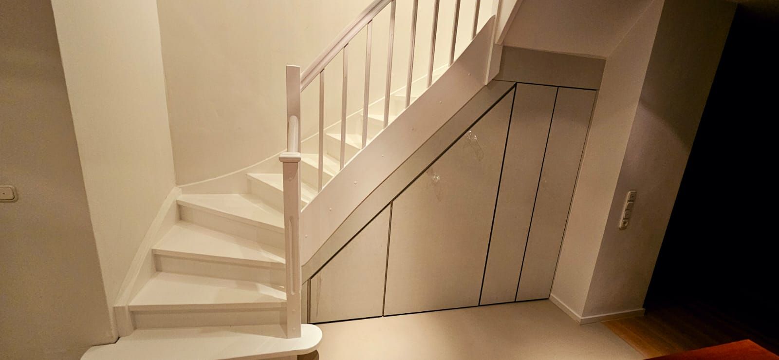 Eine weiße Treppe mit einem Einbauschrank darunter.