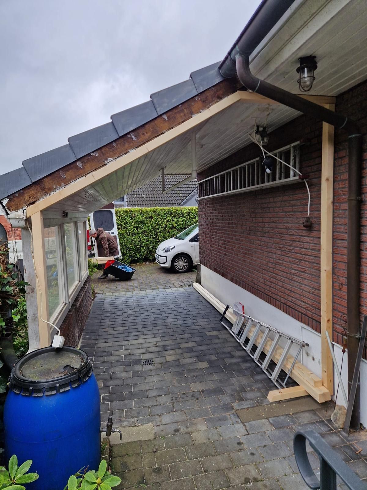 Vor einem Backsteingebäude steht ein blaues Fass.