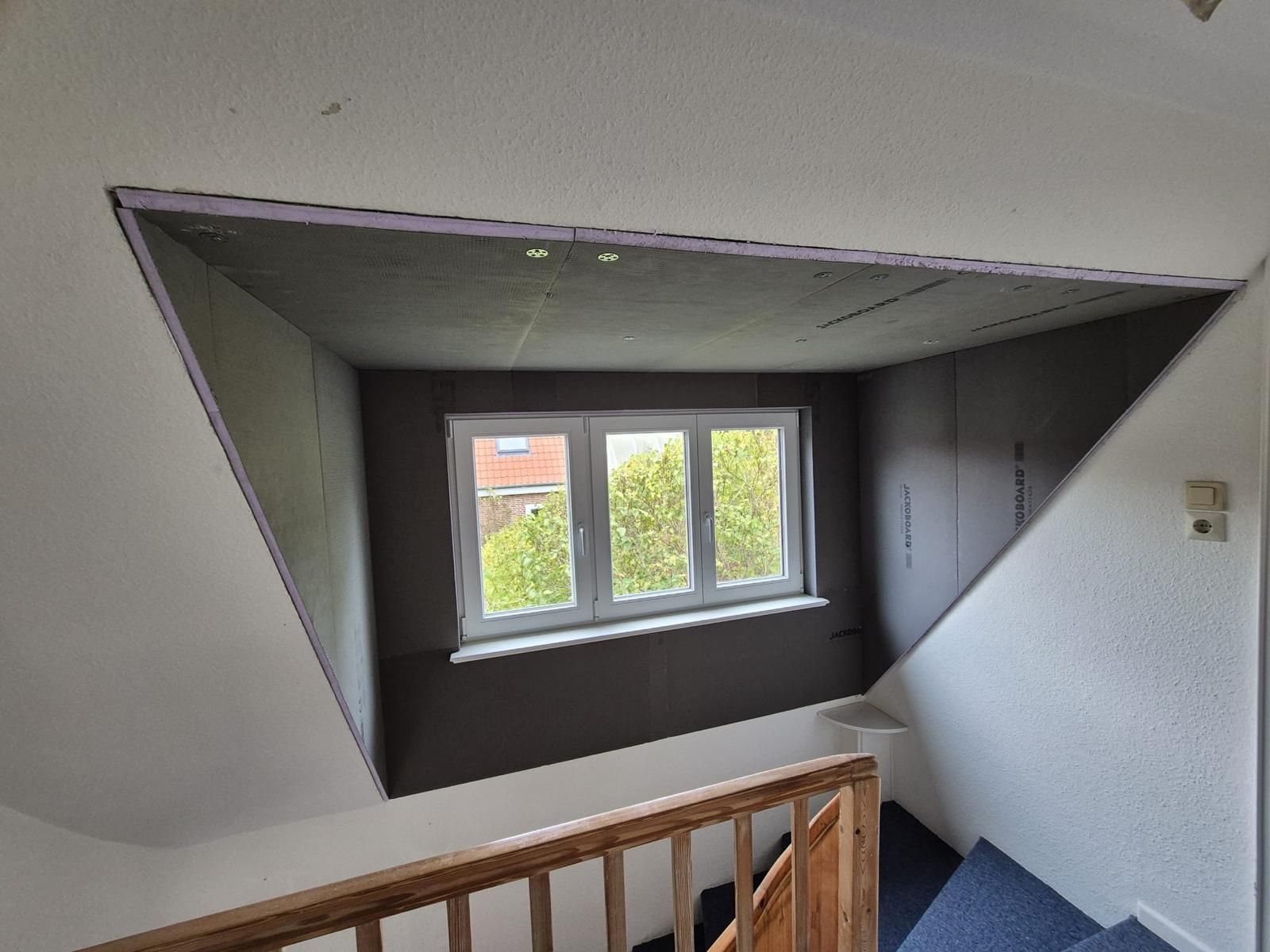 Eine Treppe mit einem Fenster in der Ecke und einem Holzgeländer.