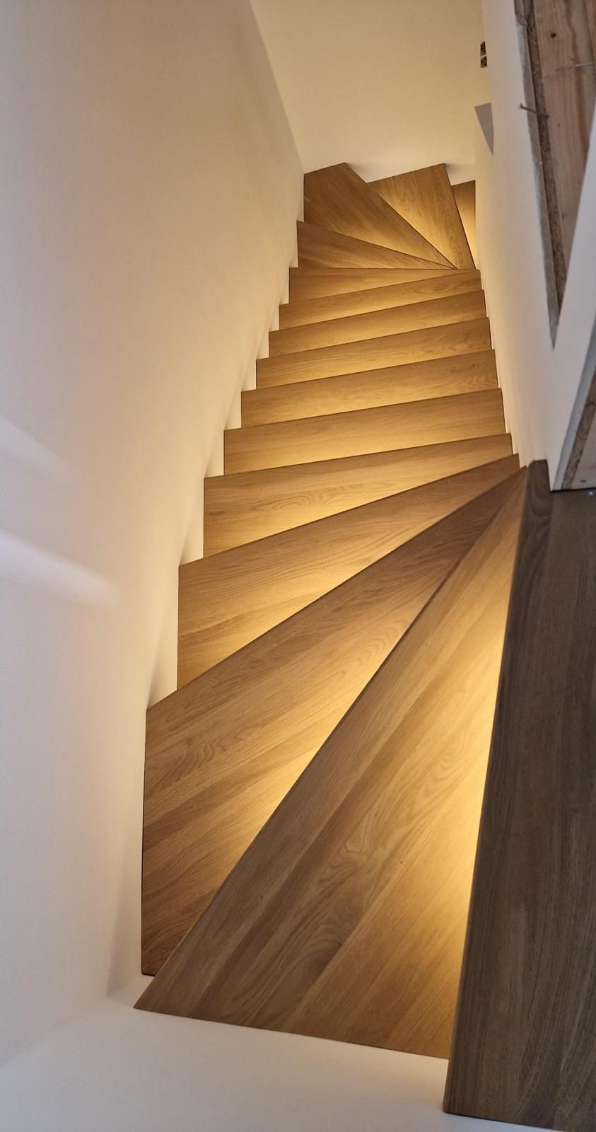 Eine hölzerne Wendeltreppe mit Licht auf den Stufen.