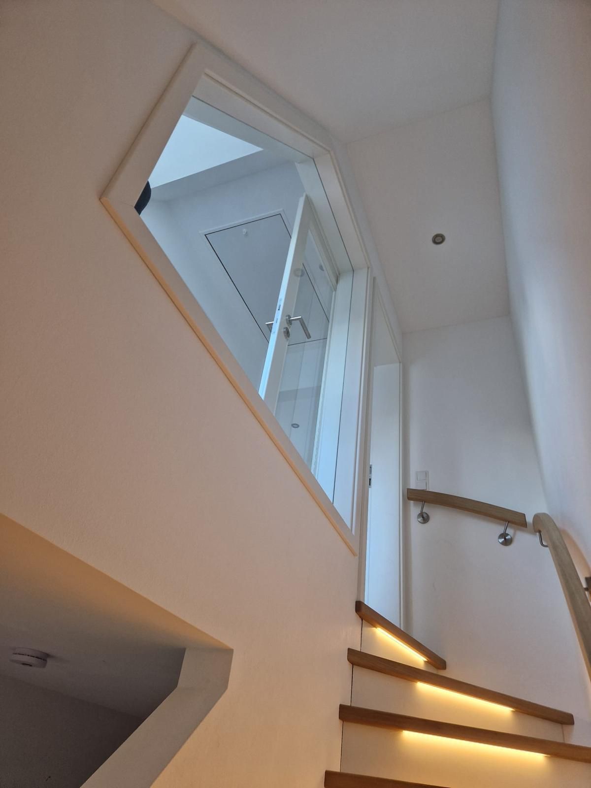 Blick nach oben auf eine Treppe mit einem Fenster in der Ecke