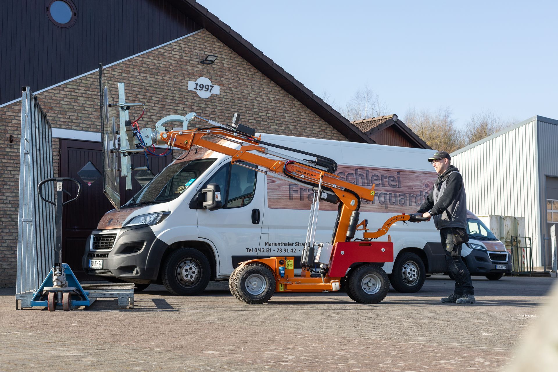 Ein Mann steht vor einem Lieferwagen, an dem ein Kran befestigt ist.