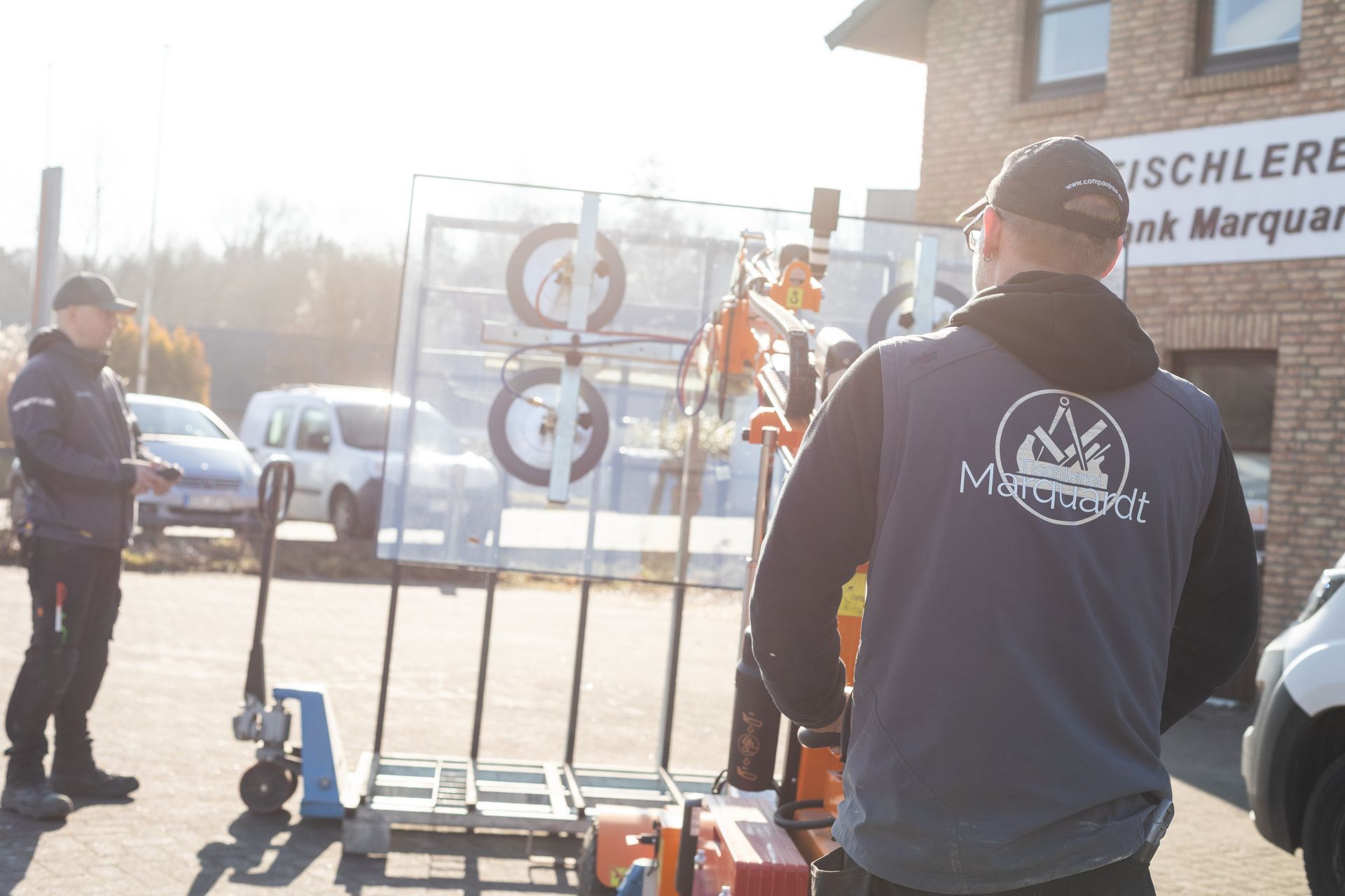 Zwei Männer stehen vor einem Backsteingebäude.