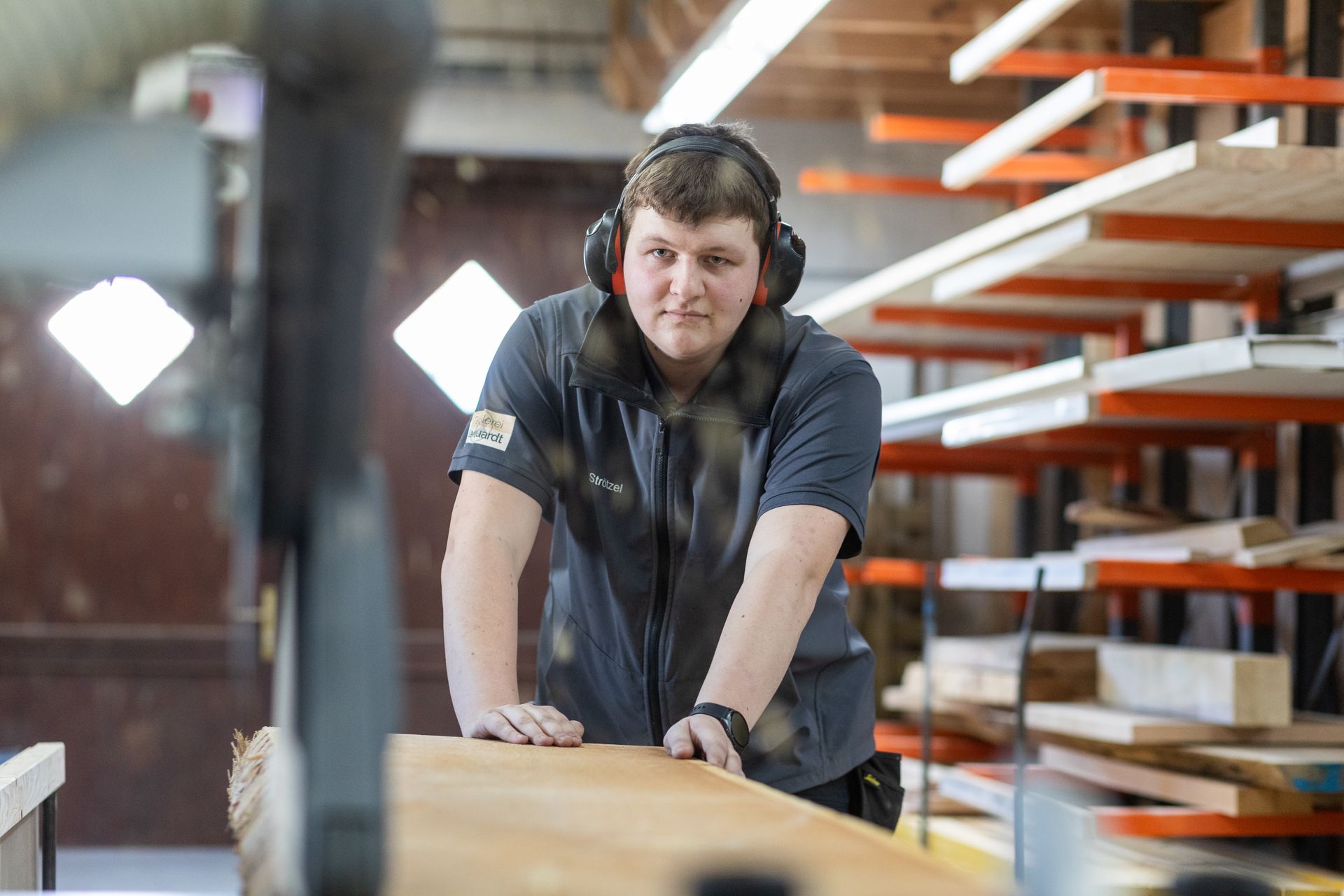 Ein Mann mit Kopfhörern schneidet ein Stück Holz.