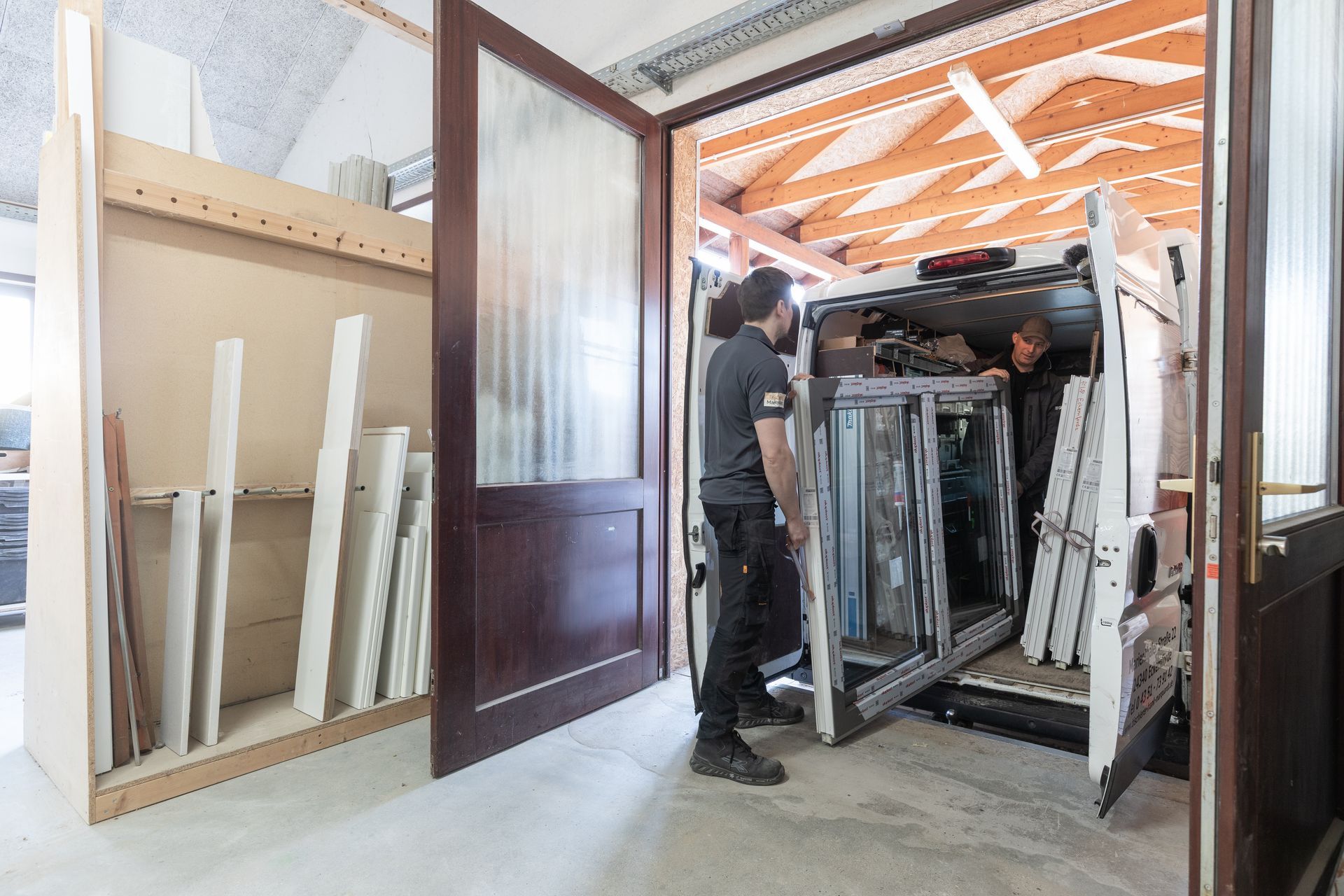Ein Mann belädt einen Lieferwagen mit einem Stapel Glas.