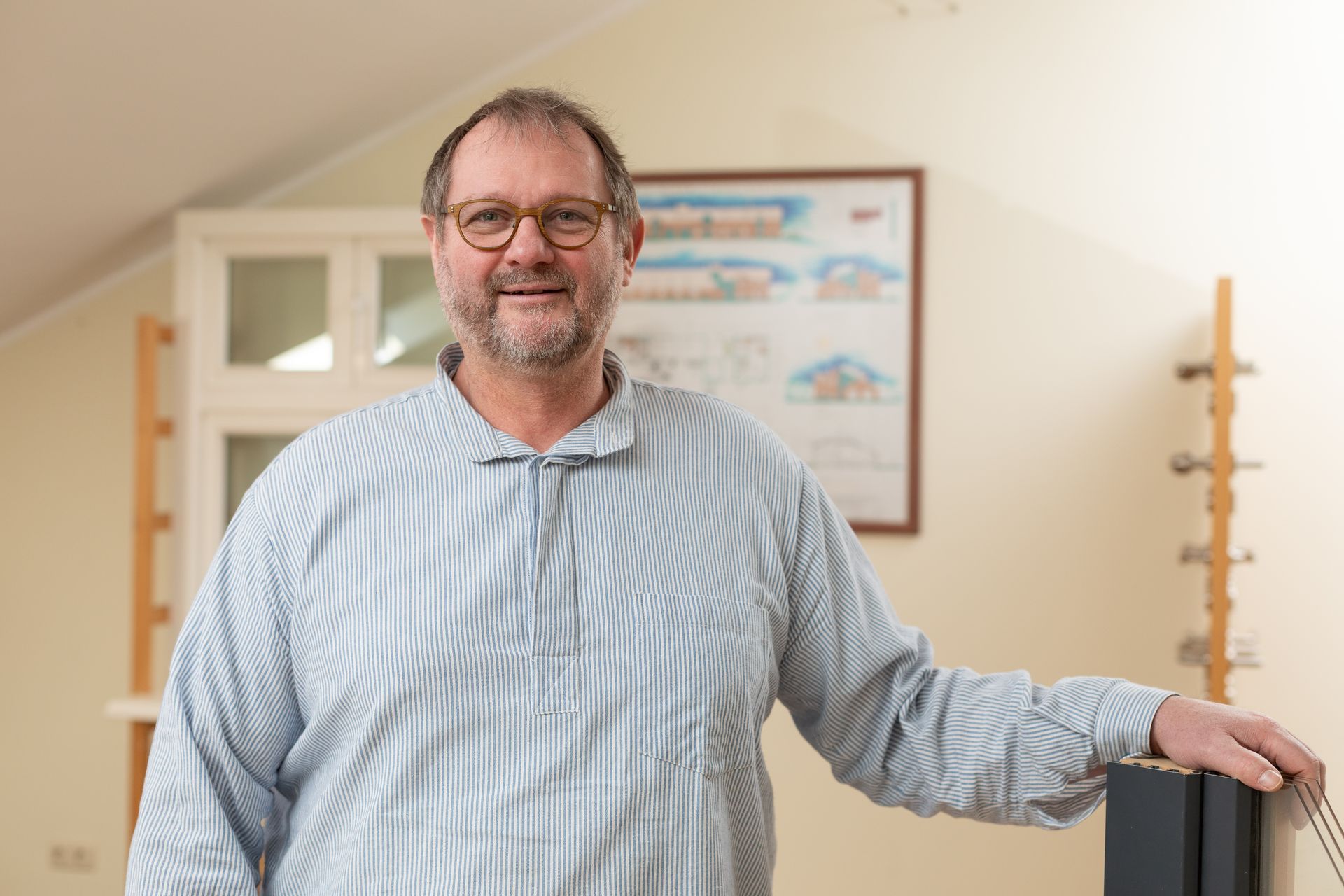 Ein Mann mit Brille und gestreiftem Hemd steht in einem Raum.