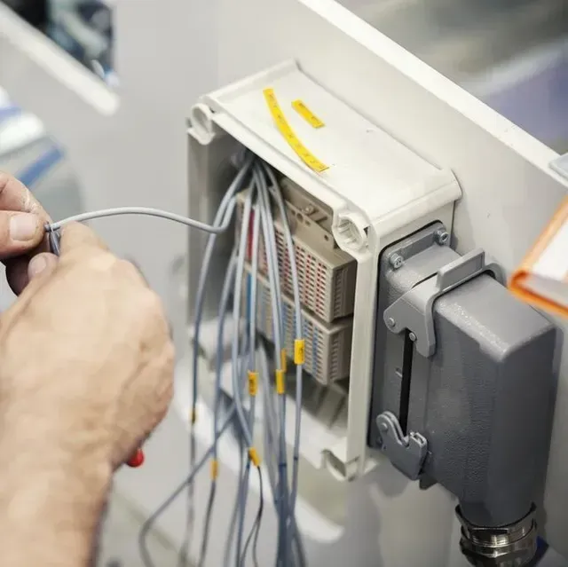 Una persona está trabajando en una caja eléctrica con cables saliendo de ella.