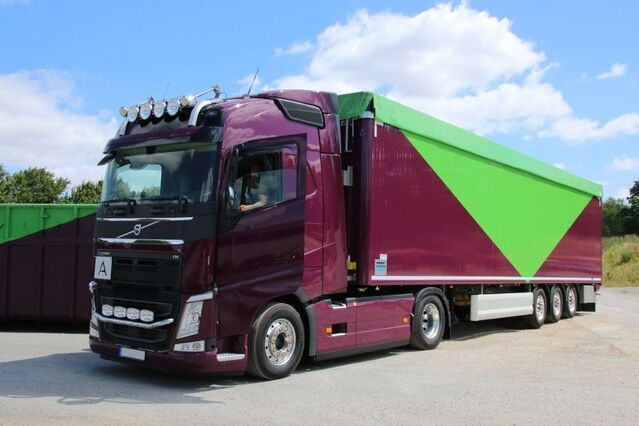Auf einem Parkplatz steht ein violett-grüner Sattelschlepper.
