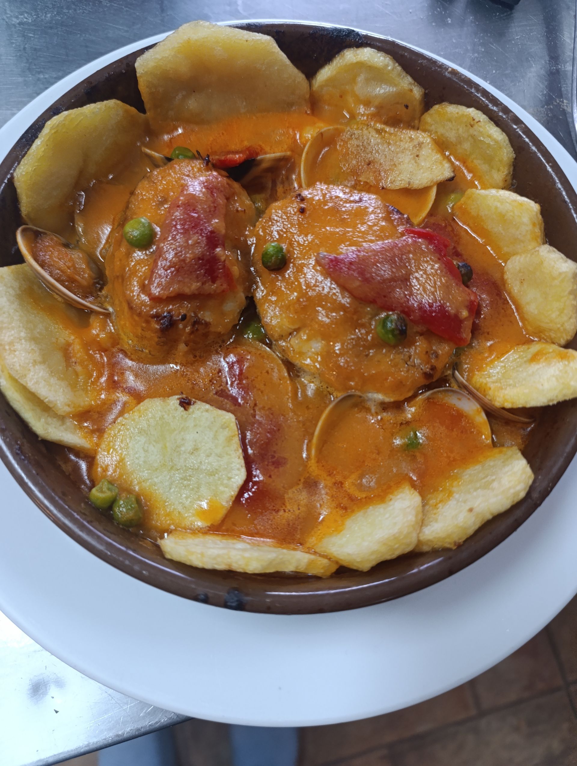 Bistec a la parrilla con patatas fritas y pimientos verdes sobre un plato negro, tabla de madera, sobre un fondo negro.