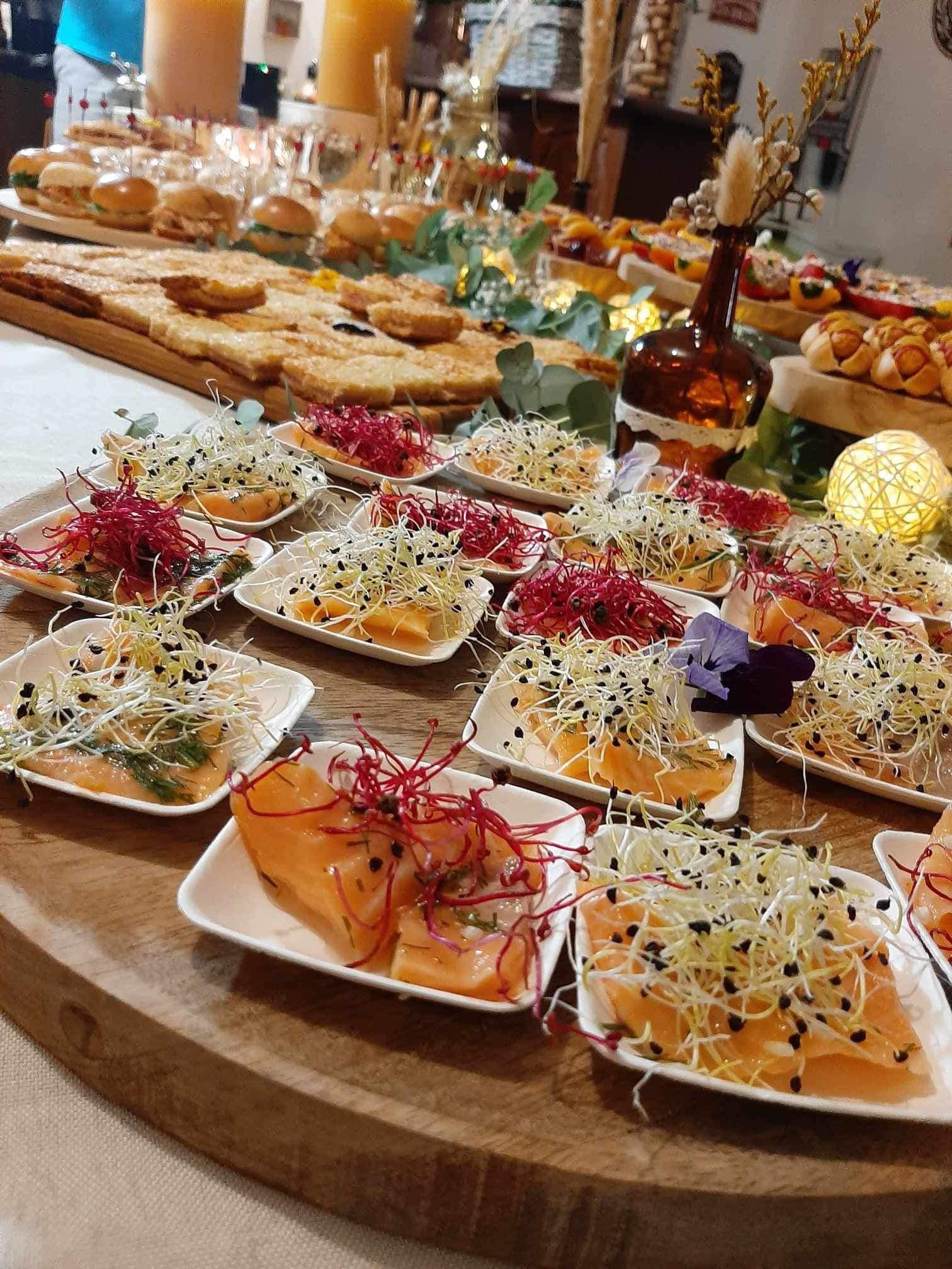 Buffet avec assortiment d'entrées, notamment des bouchées de saumon garnies de germes et de condiments.