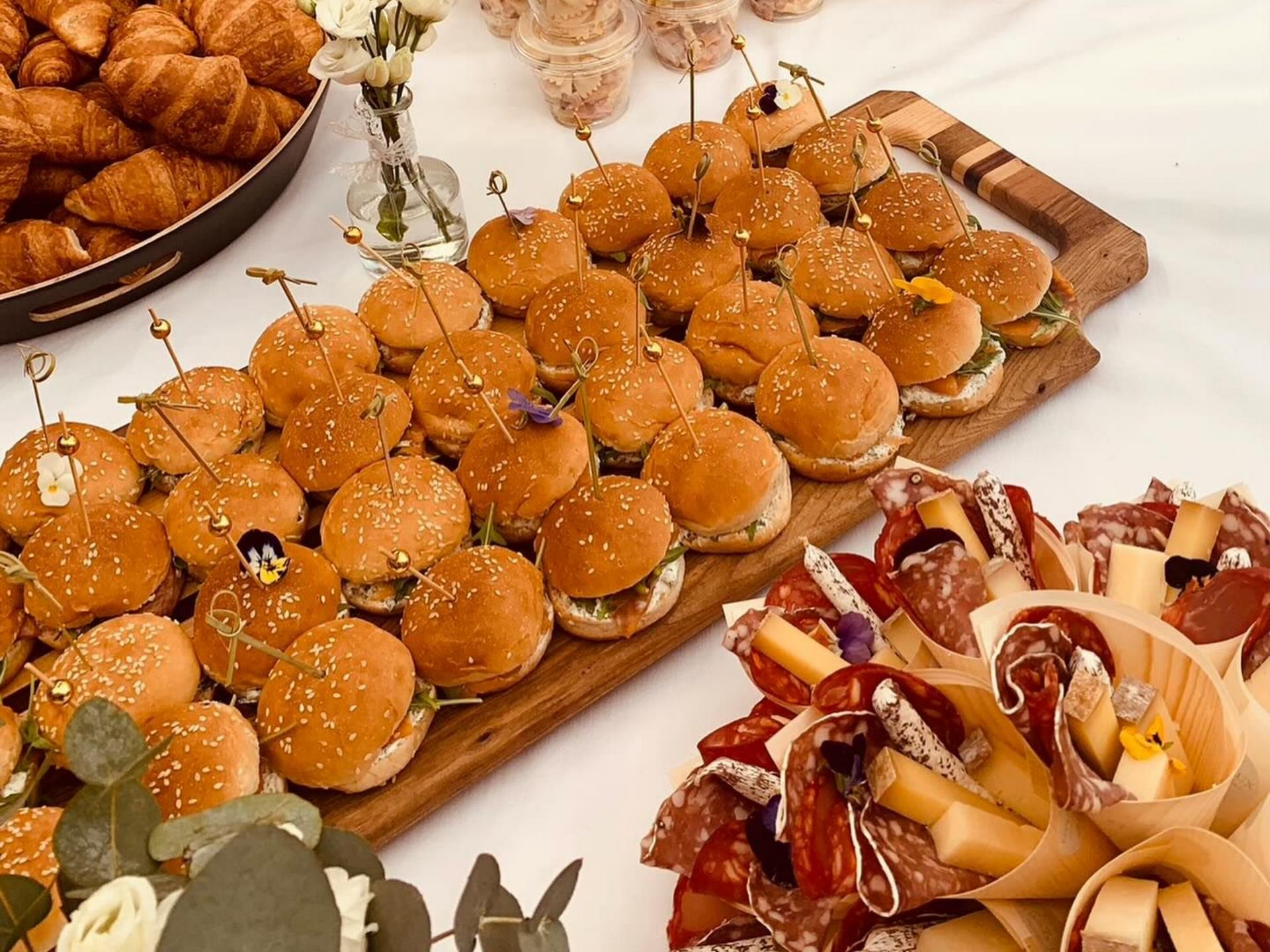 En-cas sur une table : miniburgers, croissants, cornets de charcuterie et de fromage.