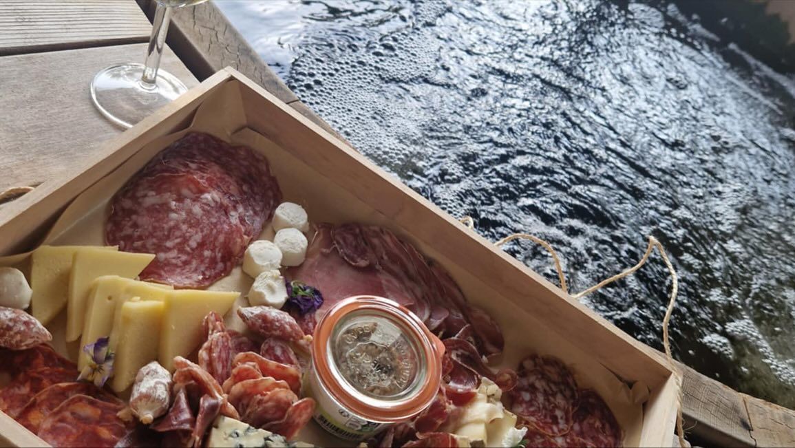 Planche de charcuterie avec viandes et fromages au bord de l'eau.