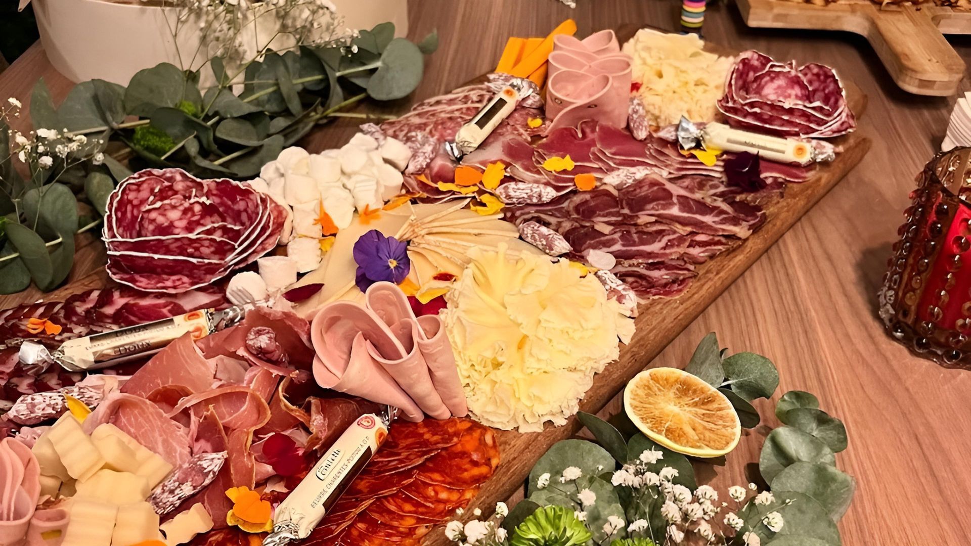 Planche de charcuterie avec assortiment de viandes, fromages et garnitures. Plateau de service en bois clair.