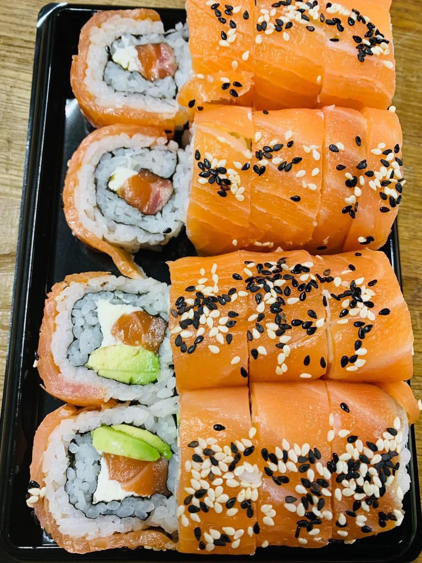 Plateau de sushis avec rouleaux de saumon, rouleaux d'avocat et graines de sésame.