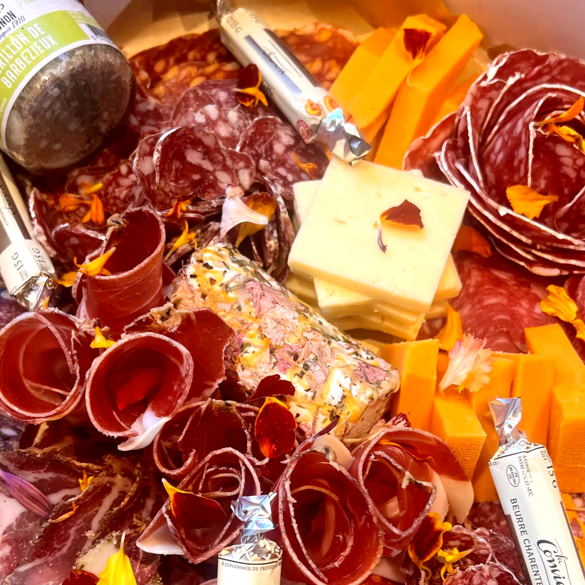 Planche de charcuterie avec un assortiment de viandes, de fromages et de garnitures, notamment du salami, du chorizo ​​et du cheddar.