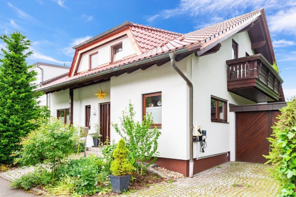 HB Holzbau Breymaier GmbH – weißes Wohnhaus mit hellroten Dachschindeln und einem Vorbau im Dachgeschoss