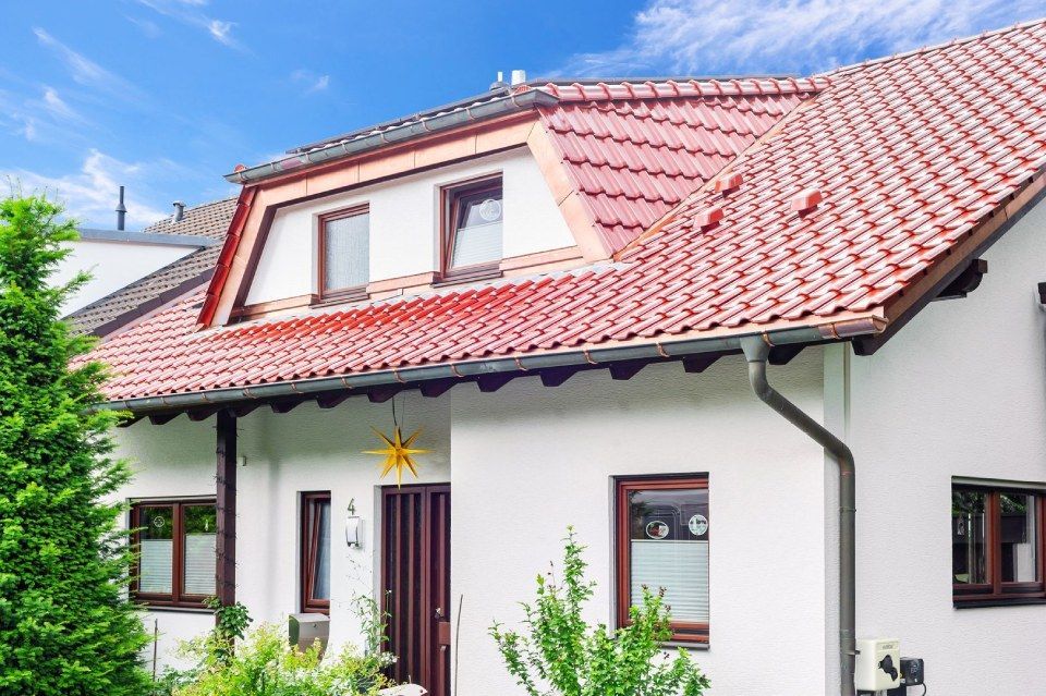 HB Holzbau Breymaier GmbH – weißes Wohnhaus mit hellroten Dachschindeln und einem Vorbau im Dachgeschoss