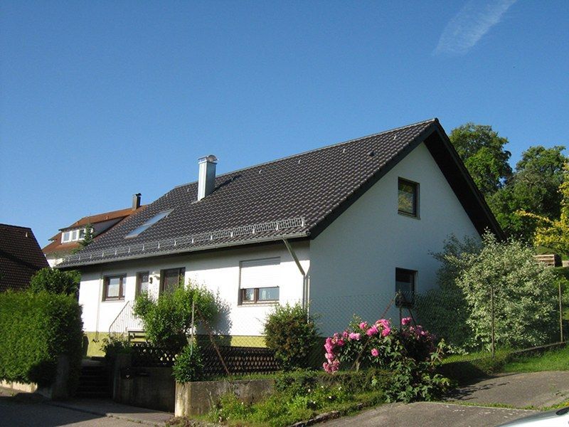 HB Holzbau Breymaier GmbH – Wohnhaus im Grünen mit weißer Fassade und dunkler Bedachung