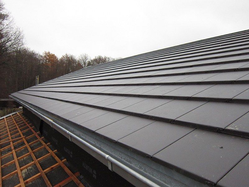 HB Holzbau Breymaier GmbH – 
Blick auf ein Dach mit dunklen, flachen Dachschindeln