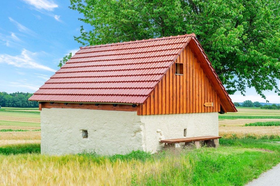 HB Holzbau Breymaier GmbH – Gebäude aus Gips und Holz mit rotem Schrägdach an einem Feld
