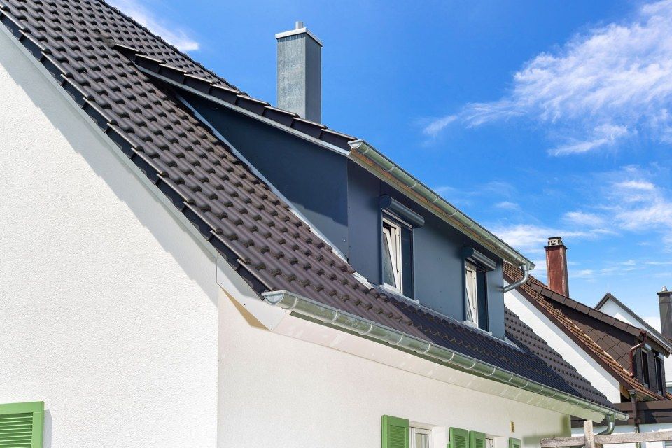 HB Holzbau Breymaier GmbH – weißes Wohnhaus mit grünen Fensterläden und schwarzem Schrägdach