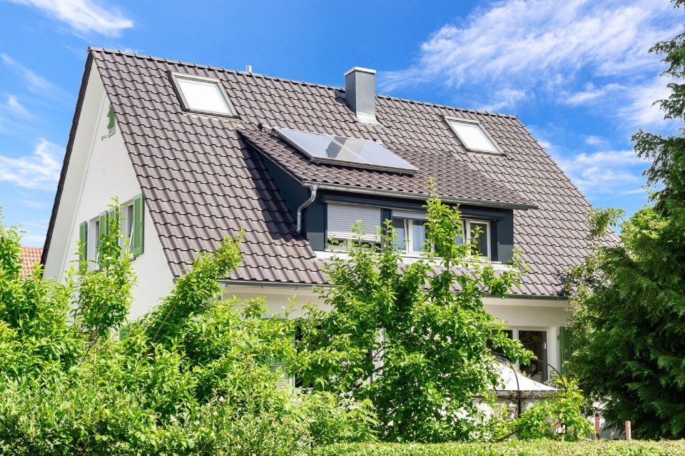 HB Holzbau Breymaier GmbH – Wohnhaus hinter Bäumen mit Schrägdach und Dachausbau sowie Solarpaneelen