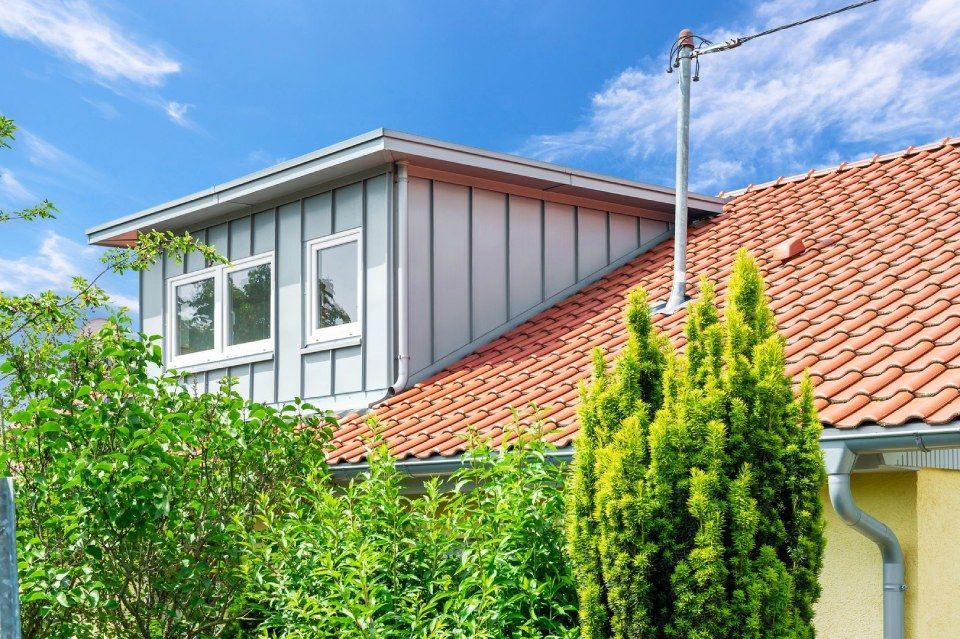 HB Holzbau Breymaier GmbH – Wohnhaus hinter Bäumen mit Schrägdach und Dachausbau, Nahaufnahme