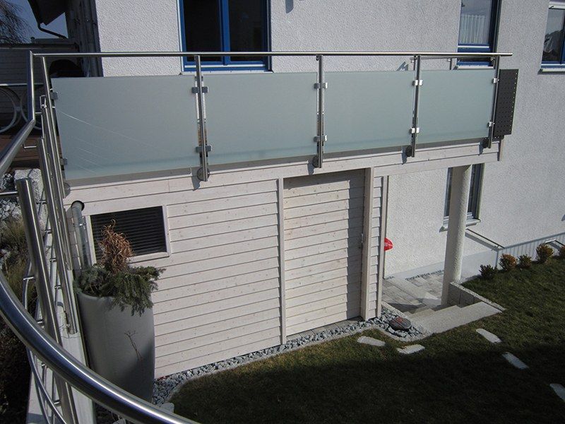 HB Holzbau Breymaier GmbH – Blick auf weiß vertäfelte Hausfassade mit verglastem Geländer darüber