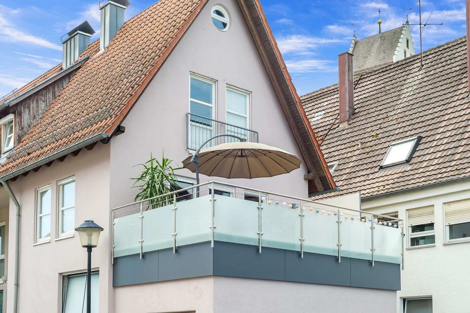 HB Holzbau Breymaier GmbH – Blick auf einen neu angelegten Balkon mit Sonnenschirm und Glasfassade