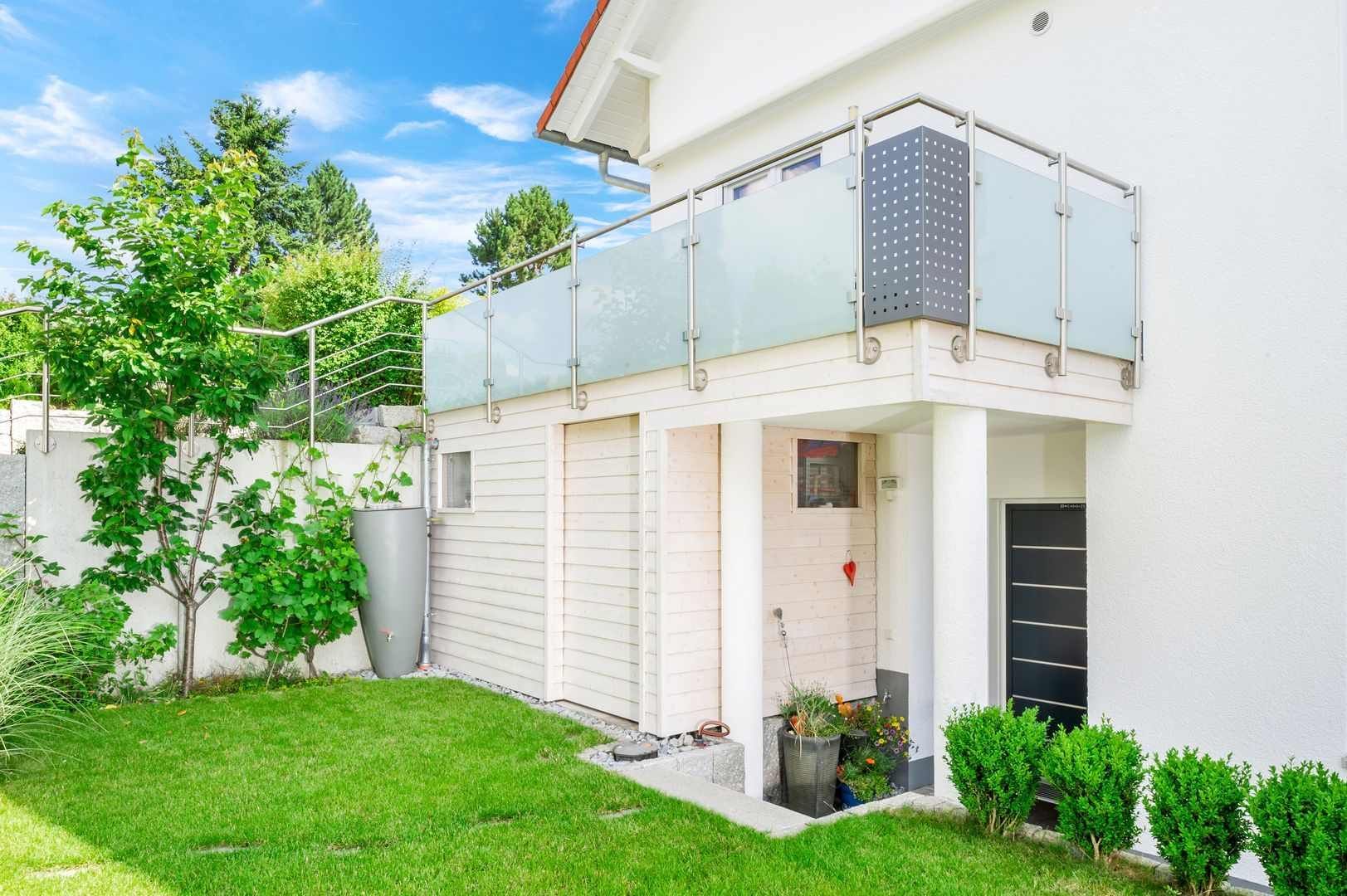 HB Holzbau Breymaier GmbH – Haus mit Garten und Balkon mit Glasgeländer