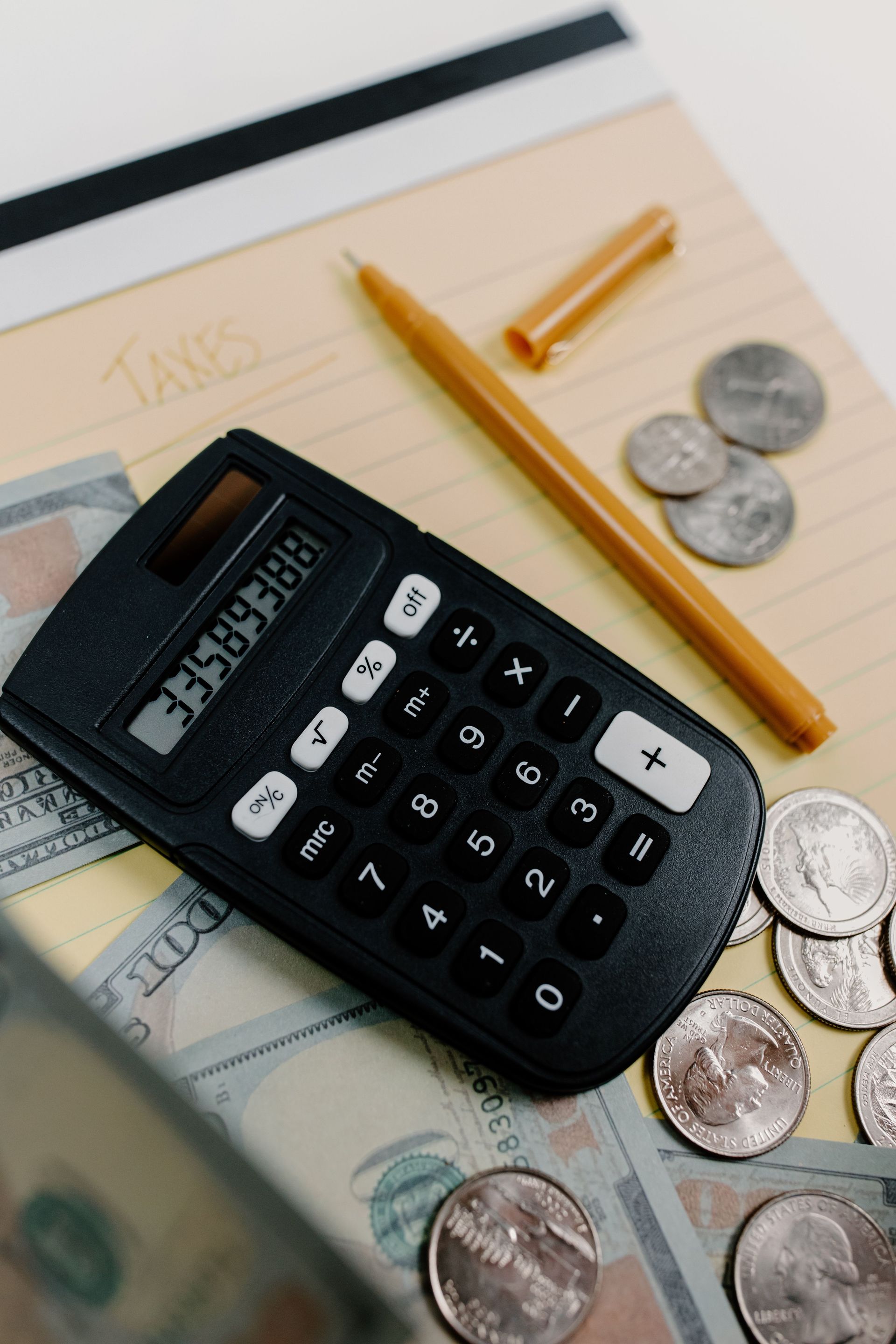 Calculator, pen, notebook, and coins on a desk, suggesting budgeting or accounting.