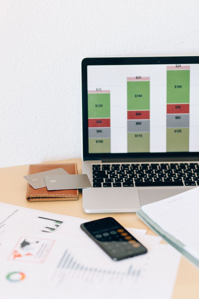 Desk with laptop showing charts, calculator, and papers on a white workspace