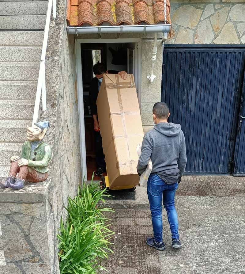 Un hombre lleva una gran caja de cartón a una casa.