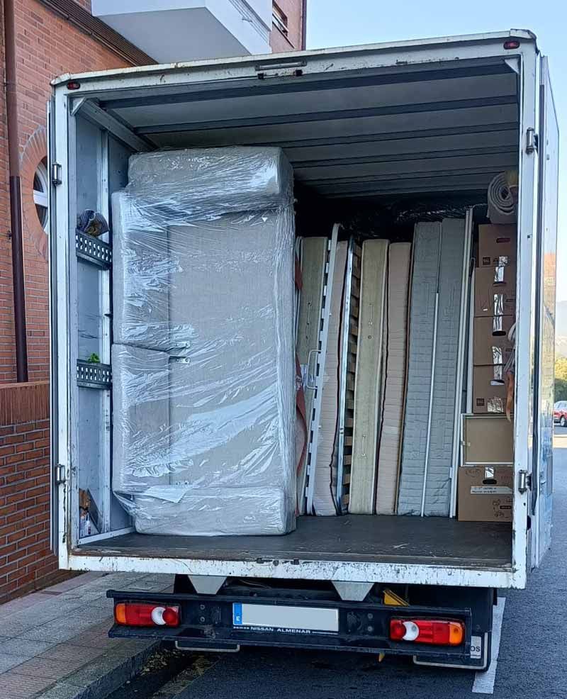 La parte trasera de un camión lleno de cajas y un refrigerador.