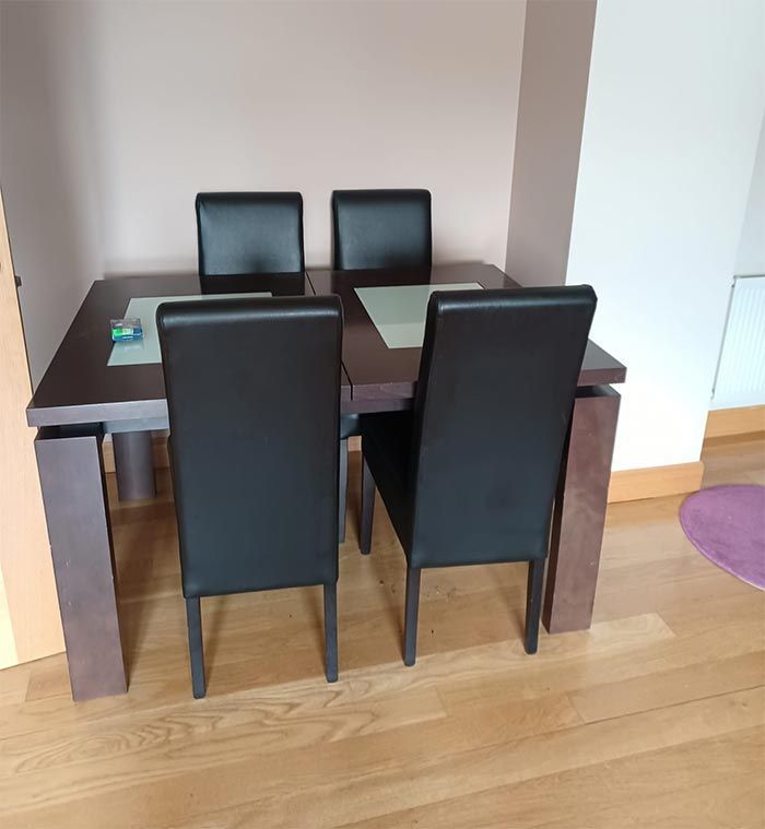 Una mesa de comedor con cuatro sillas negras.
