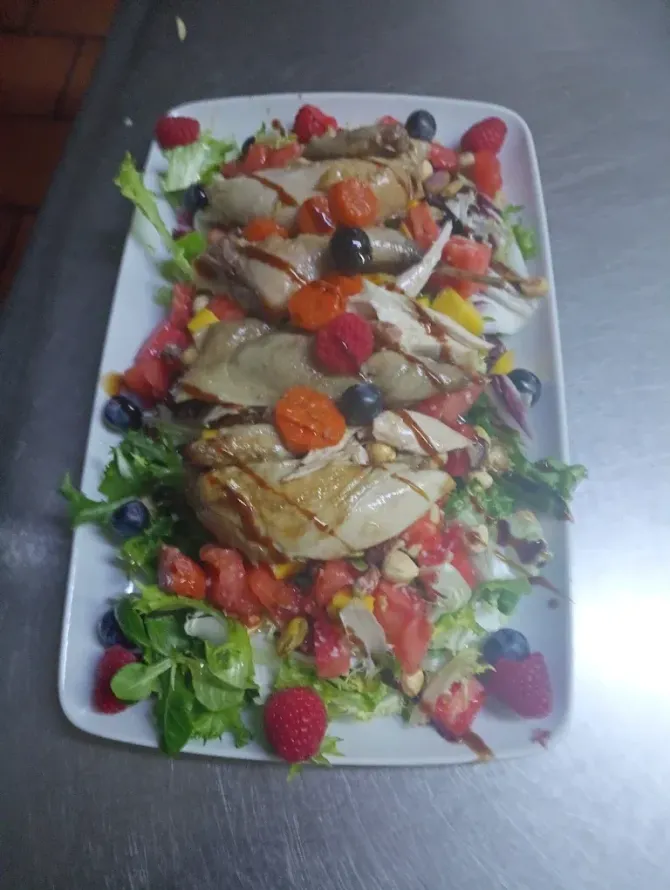 Ensalada con lechuga, aguacate, nueces, tomates y glaseado balsámico en un plato blanco.