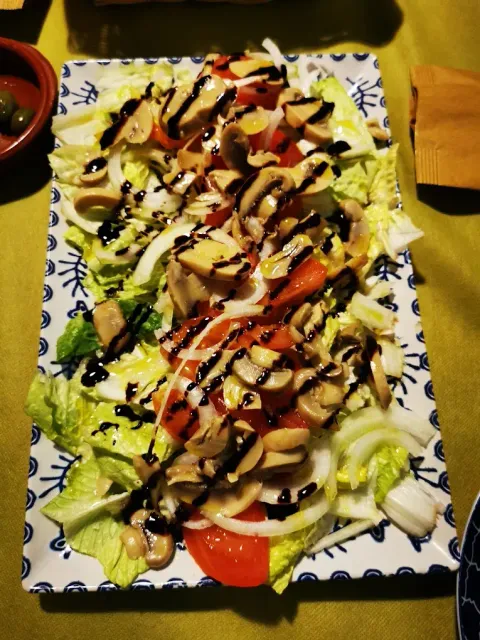 Un plato rectangular con una hogaza de pan, cubierto con hamburguesas y salsa marrón.