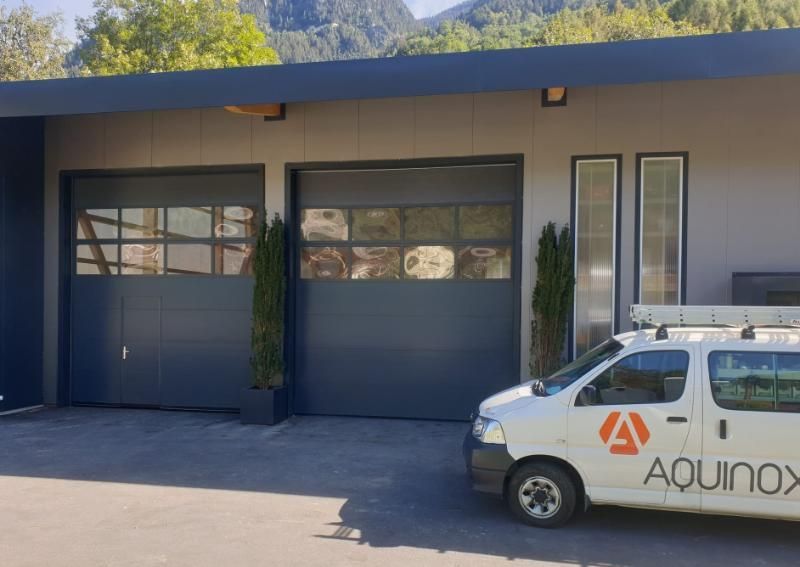 Une camionnette aquinox blanche est garée devant un immeuble