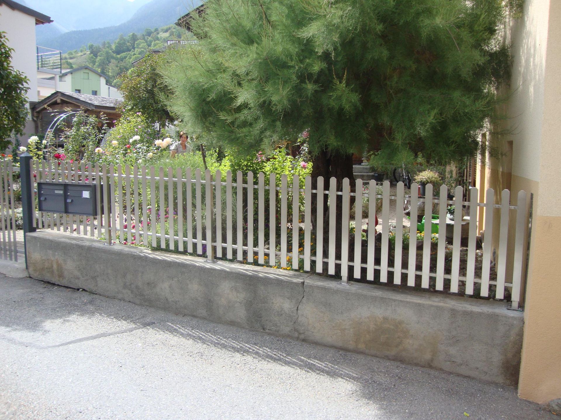 Une clôture métallique blanche avec une boîte aux lettres en arrière-plan